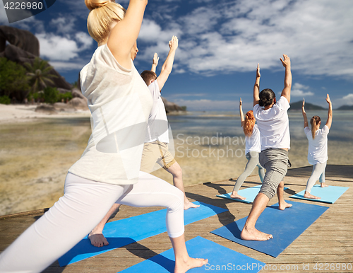 Image of group of people making yoga exercises outdoors