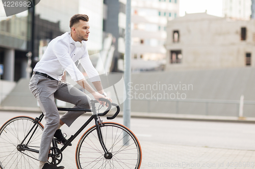 Image of man with headphones riding bicycle on city street