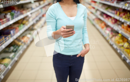 Image of woman with smartphone at shop or supermarket