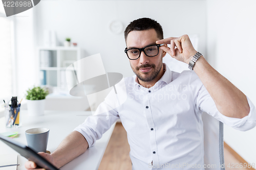 Image of businessman in glasses with tablet pc at office