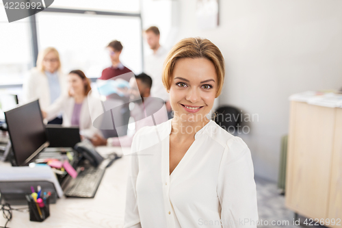 Image of happy young woman over creative team in office