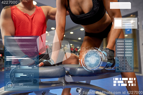 Image of young couple with dumbbell flexing muscles in gym