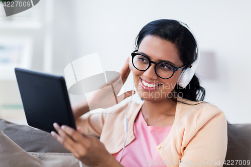 Image of happy woman with tablet pc and headphones at home