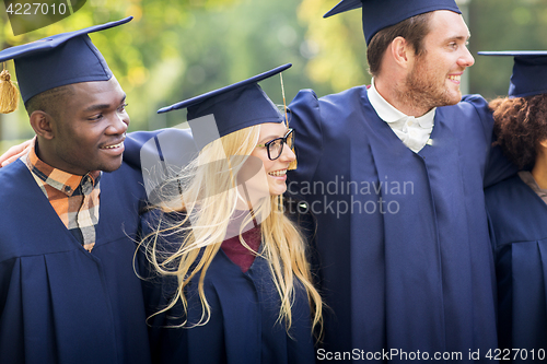 Image of happy students or bachelors in mortar boards