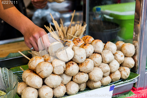 Image of seller hand with meatballs at street market