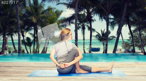 Image of woman making yoga in twist pose on mat