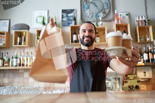 Image of man or waiter with coffee and paper bag at bar