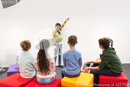 Image of happy student boy showing something at white wall