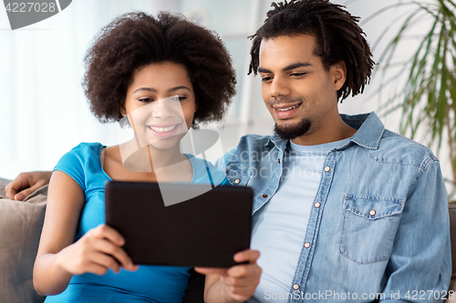 Image of smiling happy couple with tablet pc at home