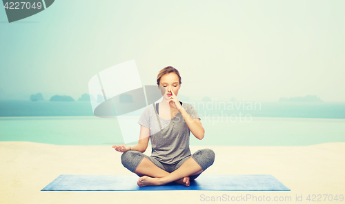 Image of woman making yoga meditation in lotus pose on mat