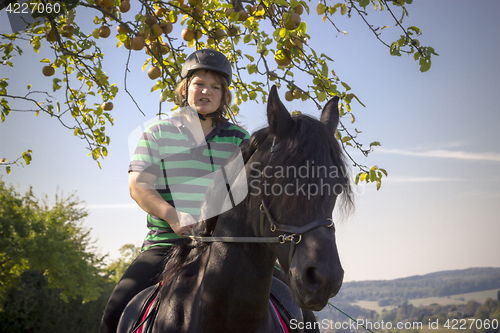 Image of Beautiful young woman rides her black Horse 