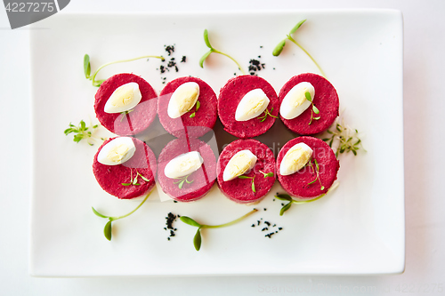 Image of layered salad with herring, beets, carrots, onions, potatoes and eggs close-up on a plate. horizontal.