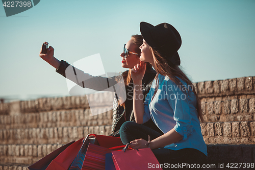 Image of Two girls walking with shopping on city streets