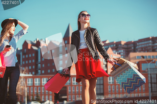 Image of Two girls walking with shopping on city streets