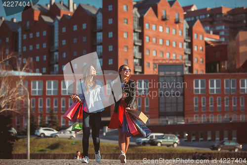Image of Two girls walking with shopping on city streets