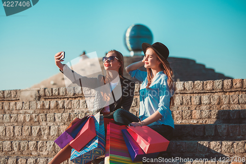 Image of Two girls walking with shopping on city streets