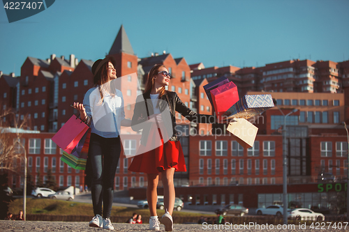 Image of Two girls walking with shopping on city streets