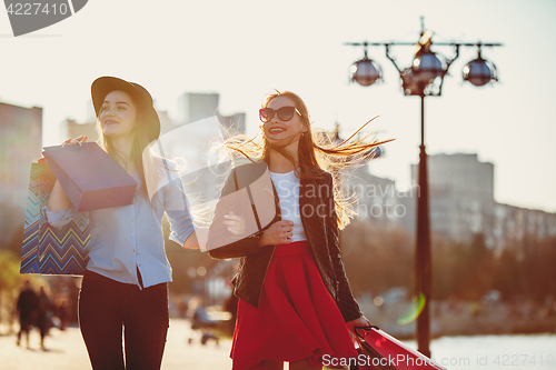 Image of Two girls walking with shopping on city streets