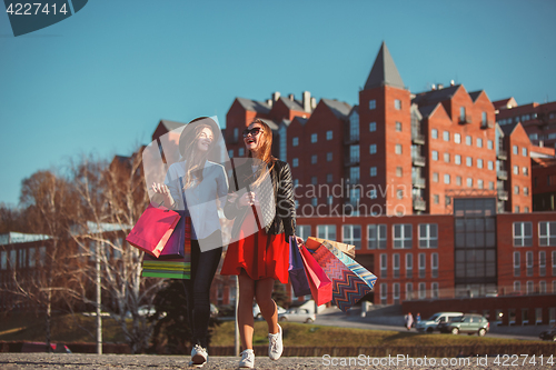 Image of Two girls walking with shopping on city streets