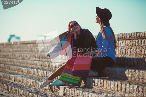 Image of Two girls walking with shopping on city streets