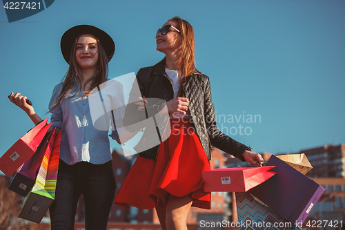 Image of Two girls walking with shopping on city streets