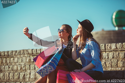 Image of Two girls walking with shopping on city streets