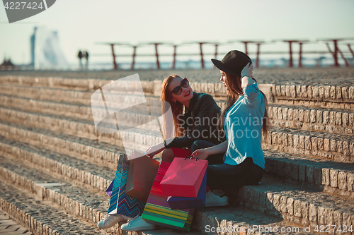 Image of Two girls walking with shopping on city streets