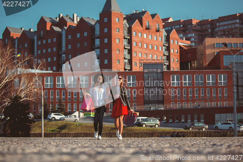 Image of Two girls walking with shopping on city streets