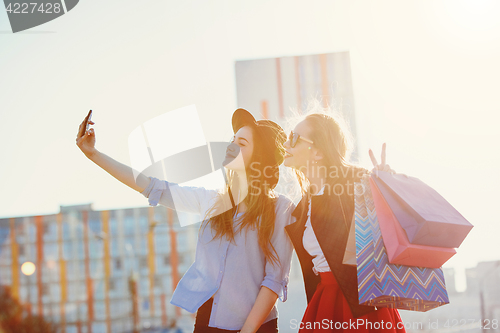 Image of Two girls walking with shopping on city streets