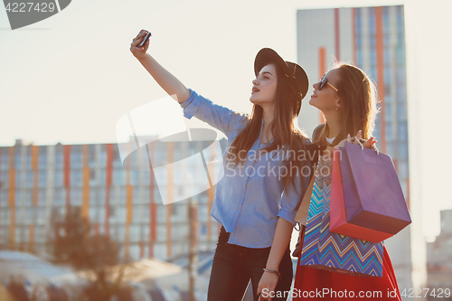 Image of Two girls walking with shopping on city streets