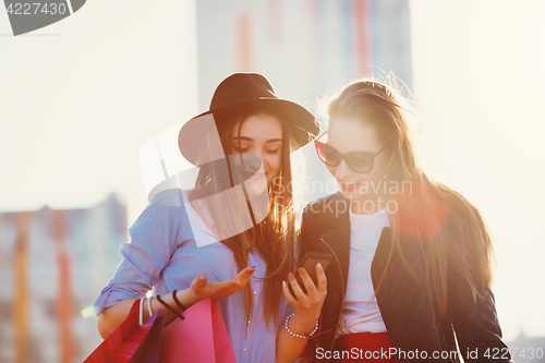 Image of Two girls walking with shopping on city streets