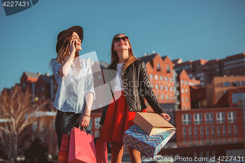 Image of Two girls walking with shopping on city streets