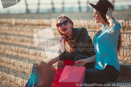 Image of Two girls walking with shopping on city streets