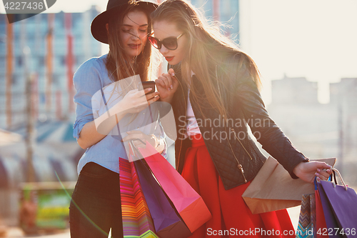 Image of Two girls walking with shopping on city streets