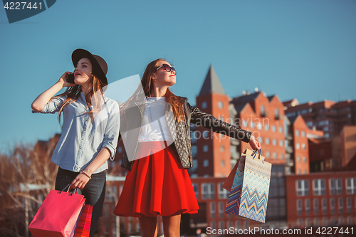 Image of Two girls walking with shopping on city streets