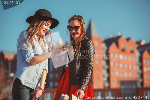 Image of Two girls walking with shopping on city streets