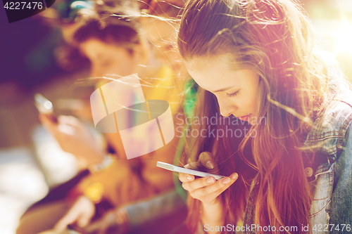 Image of happy teenage friends with smartphones outdoors