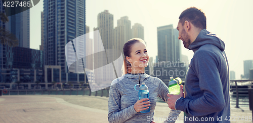 Image of smiling couple with bottles of water in city