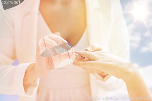 Image of close up of lesbian couple hands with wedding ring