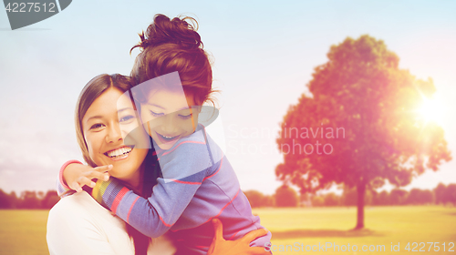 Image of happy mother and daughter hugging outdoors