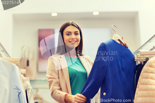 Image of happy young woman choosing clothes in mall