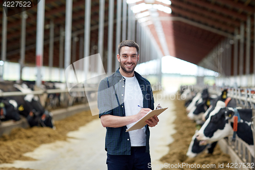 Image of farmer with clipboard and cows in cowshed on farm