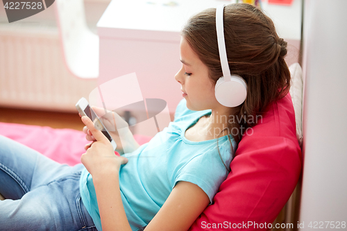 Image of happy girl with smartphone and headphones at home