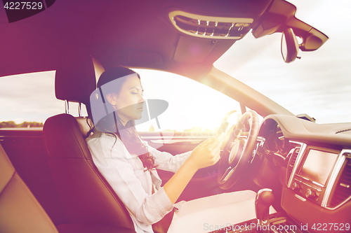 Image of woman driving car with smarhphone