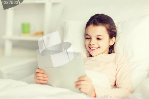 Image of happy girl lying in bed with tablet pc at home