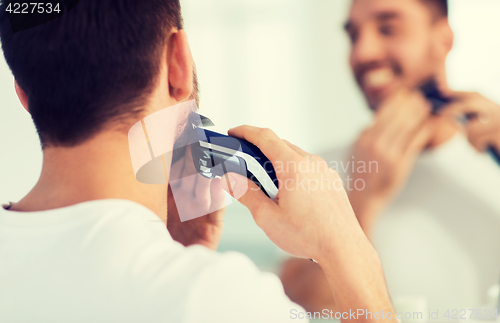 Image of close up of man shaving beard with trimmer