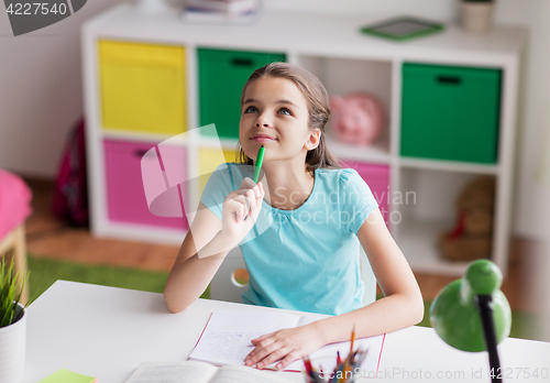 Image of happy girl with book and notebook dreaming at home