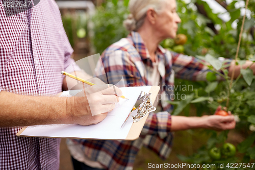Image of senior couple with clipboard at farm