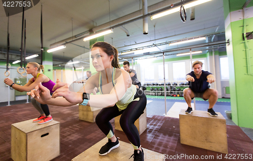 Image of group of people doing box jumps exercise in gym