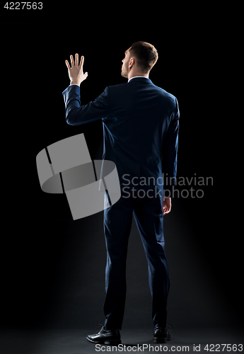 Image of businessman in suit touching something invisible